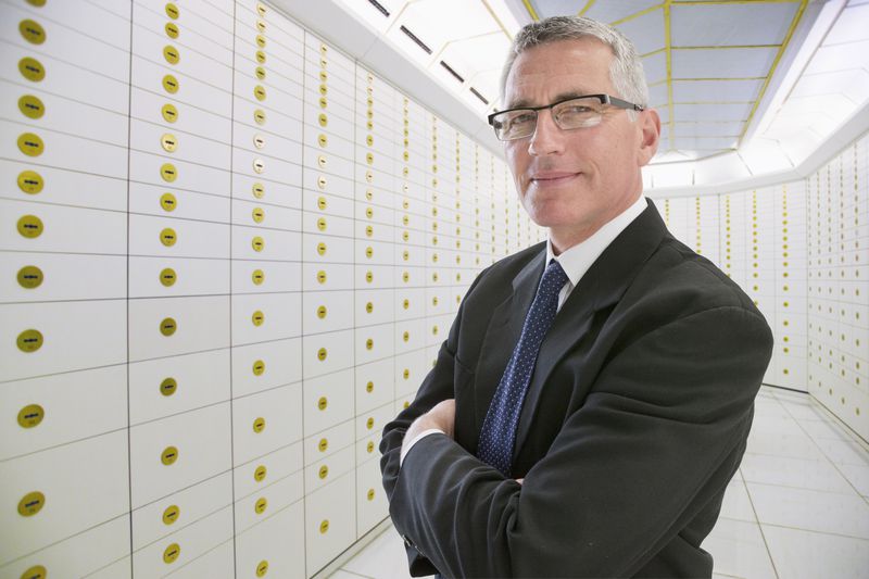 Businessman Standing In Safety Deposit Vault.