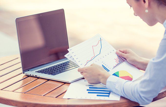  Woman reviewing stock charts in front of laptop