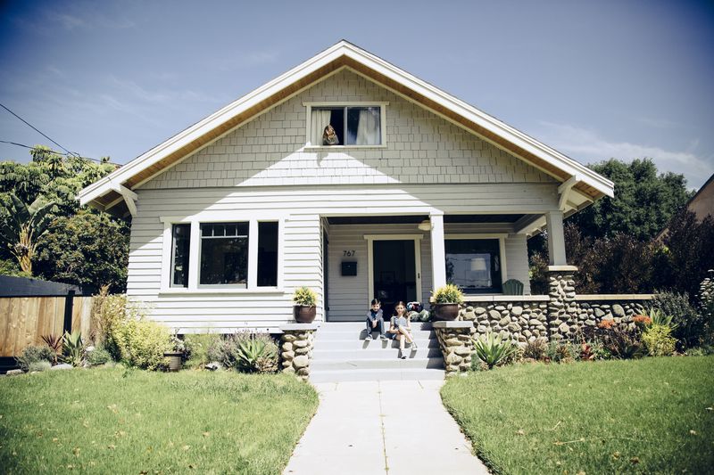 a boy and a girl sit on the front steps of a house