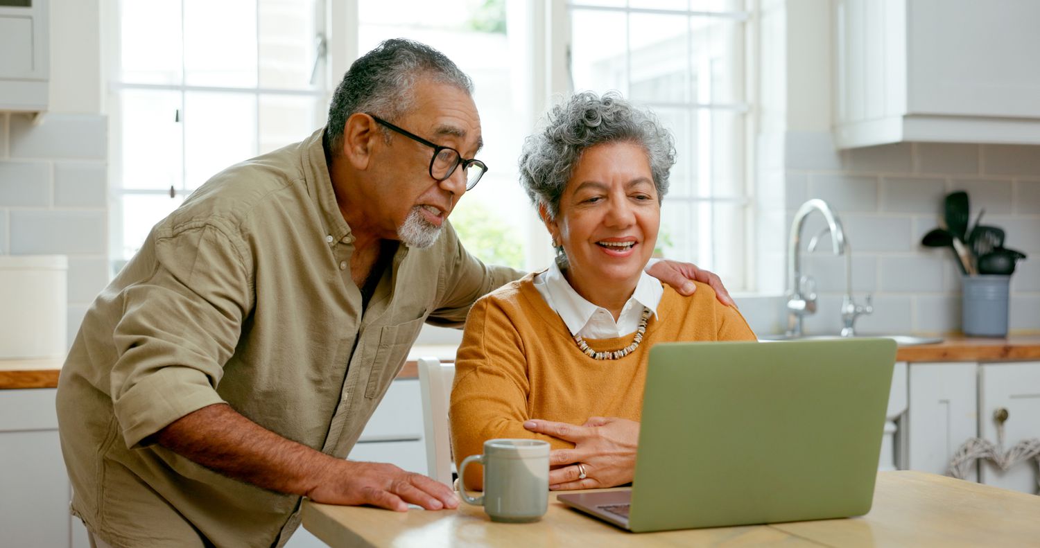 Senior couple looking at a laptop in their kitchen. 