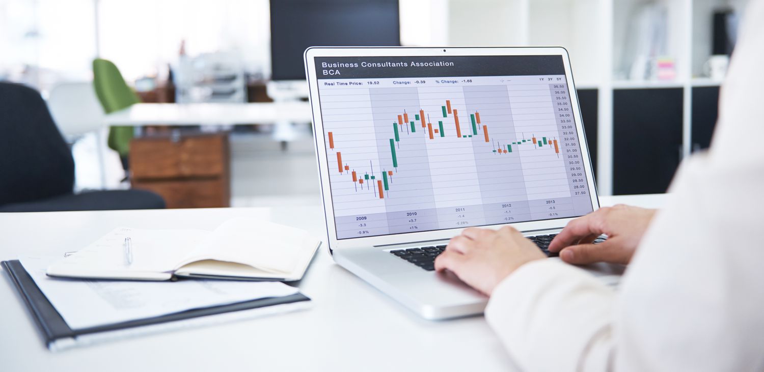 Investor looking at a candlestick chart on their monitor.