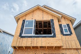 An under-construction home is seen in front of a clouded sky.