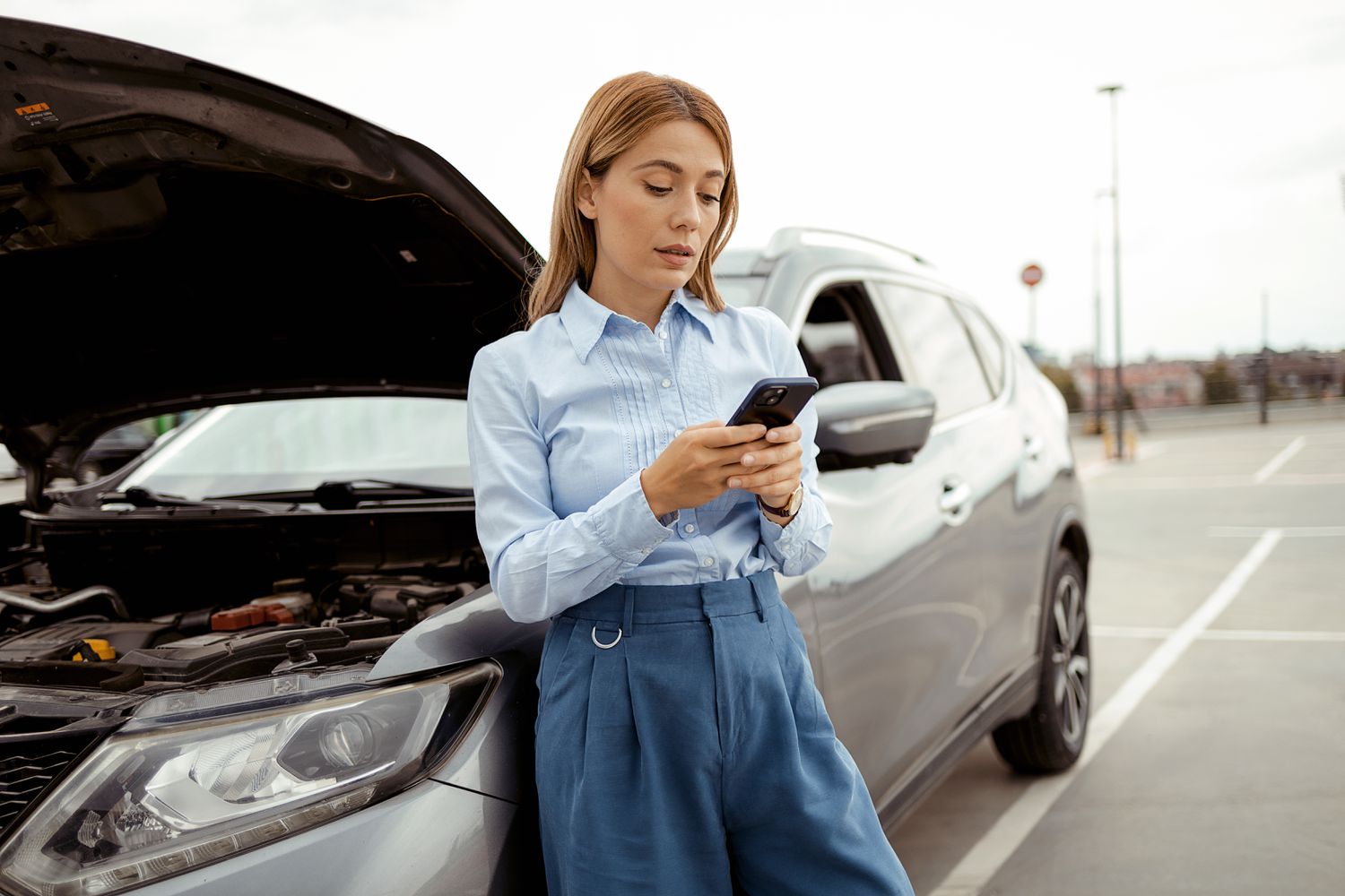 Woman with car trouble waits for emergency help.