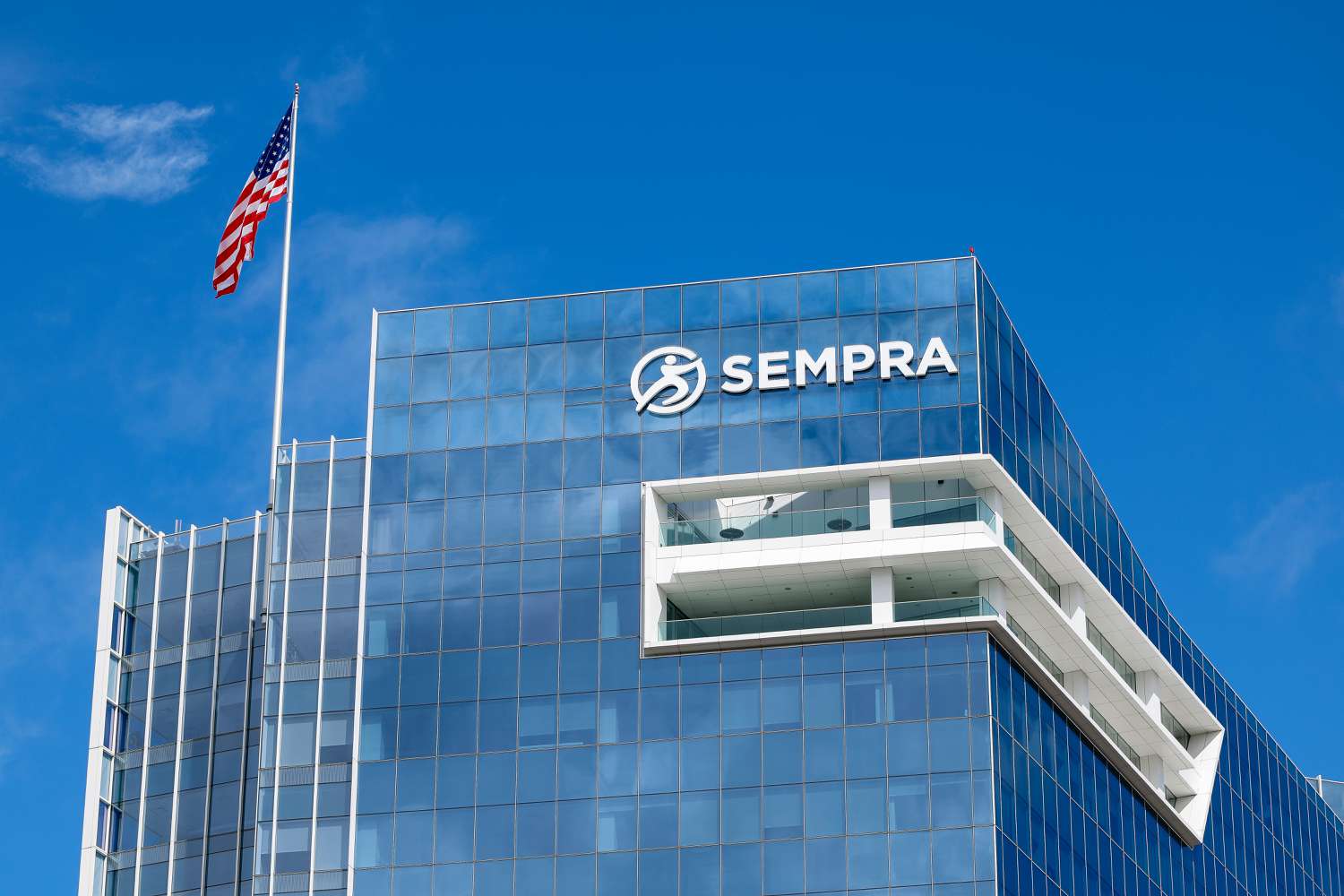 White Sempra logo on the side of a building, with an American flag and blue sky in the background