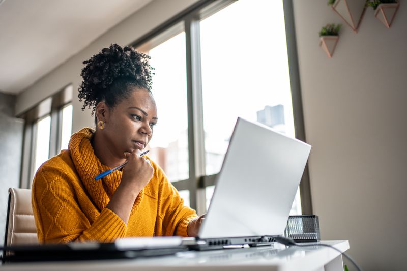 Black woman working from office at laptop