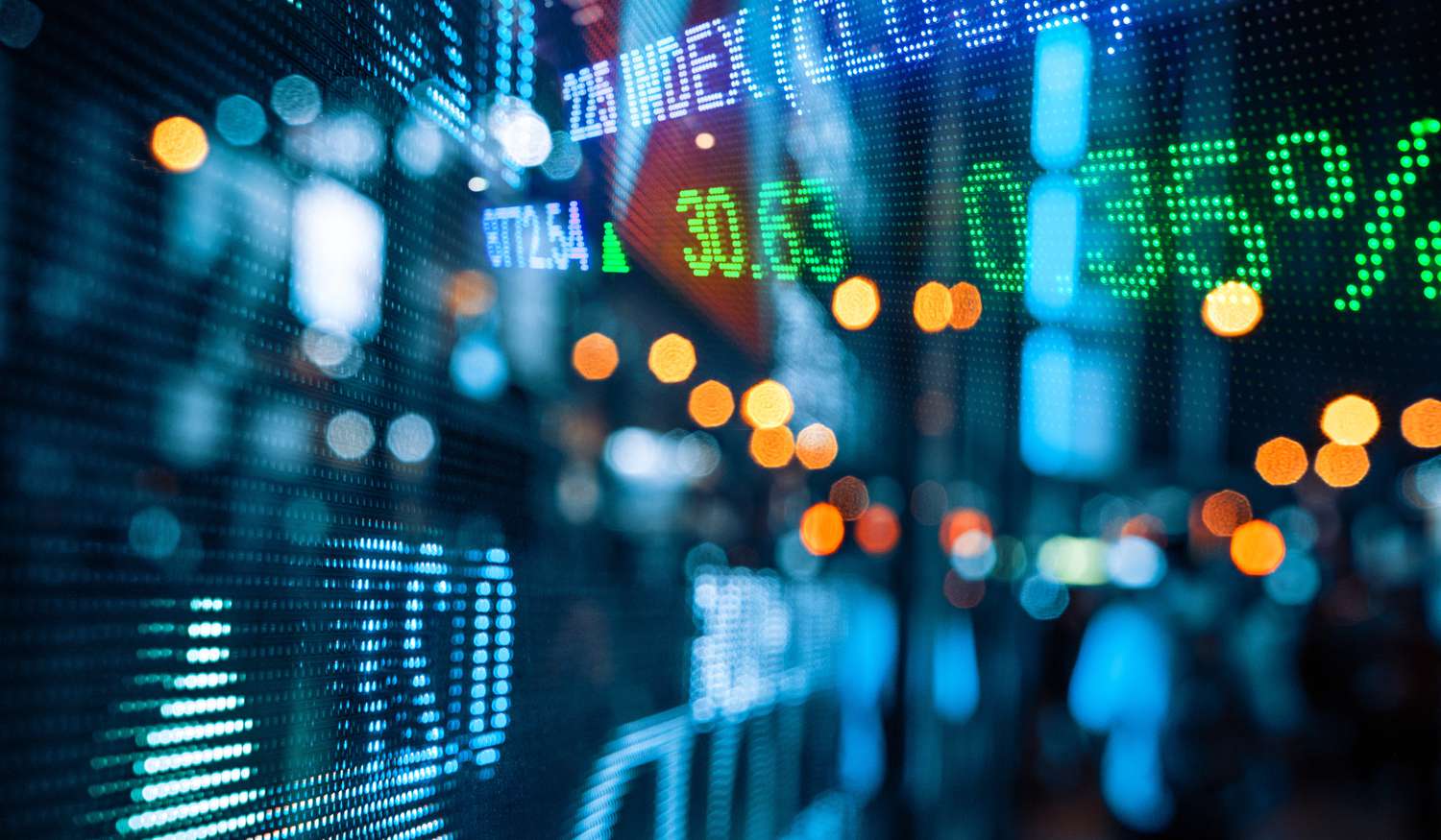 Display of stock market quotes with city scene reflected on glass