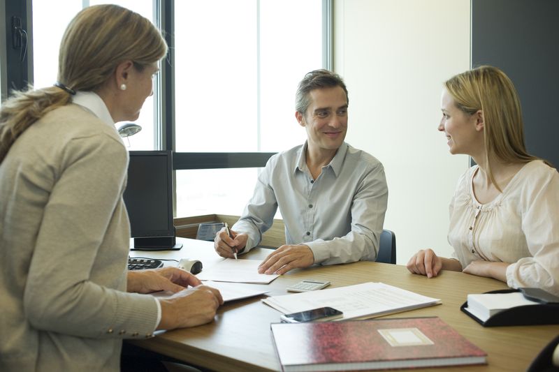 A couple sign documents in an office setting.