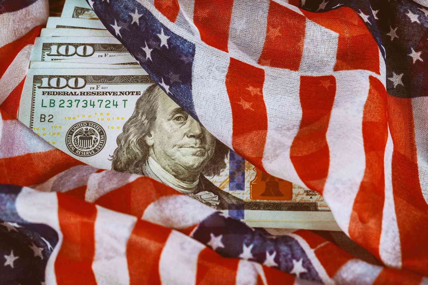 US Flag wrapped around hundred dollar bills.