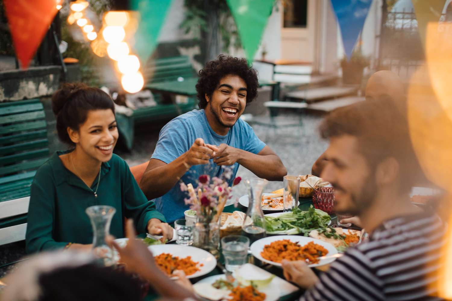 A group of friends sitting down outside and enjoying dinner.