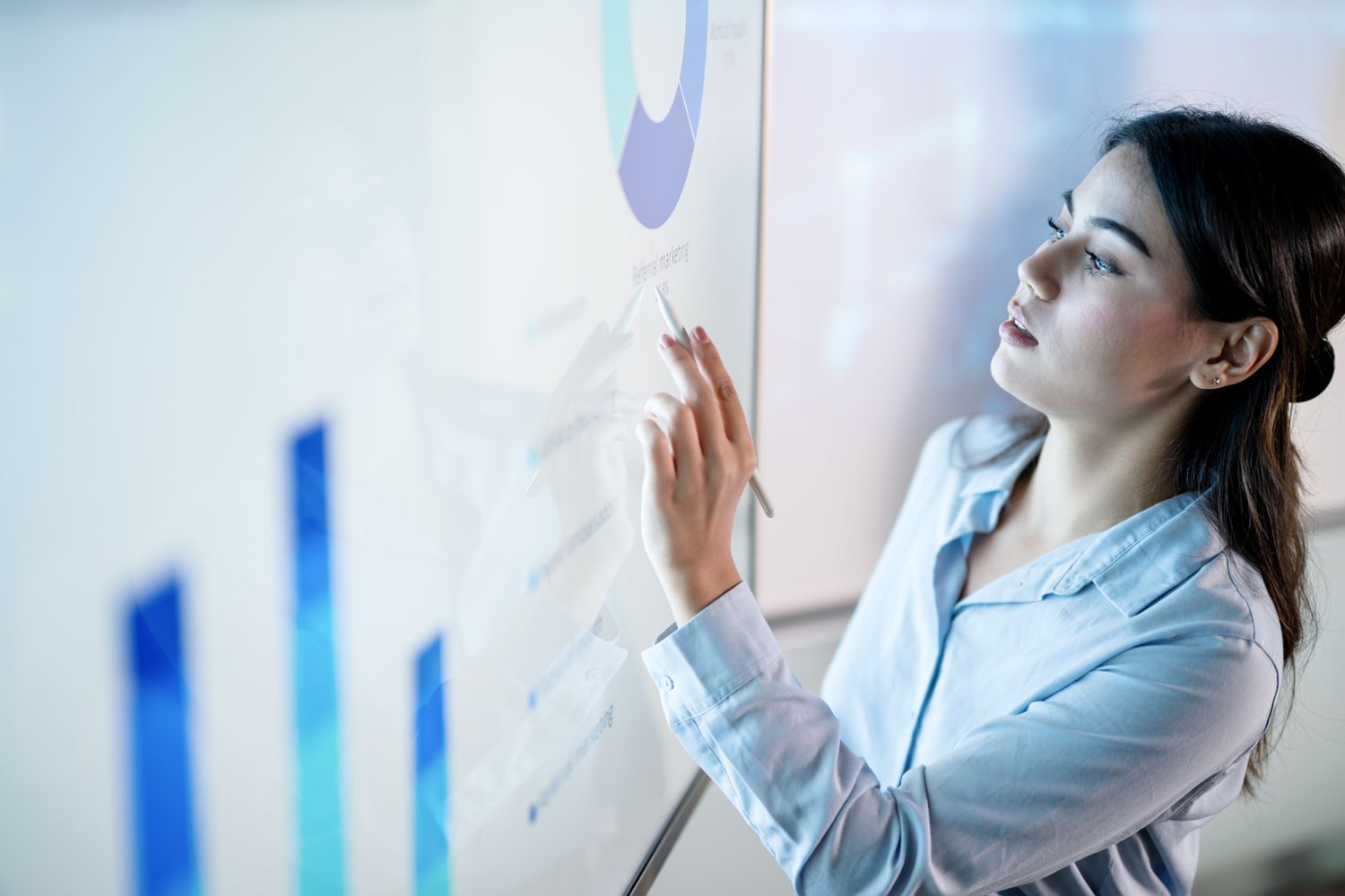A person digital pen in hand pointing at financial analysis on a wall-sized screen.