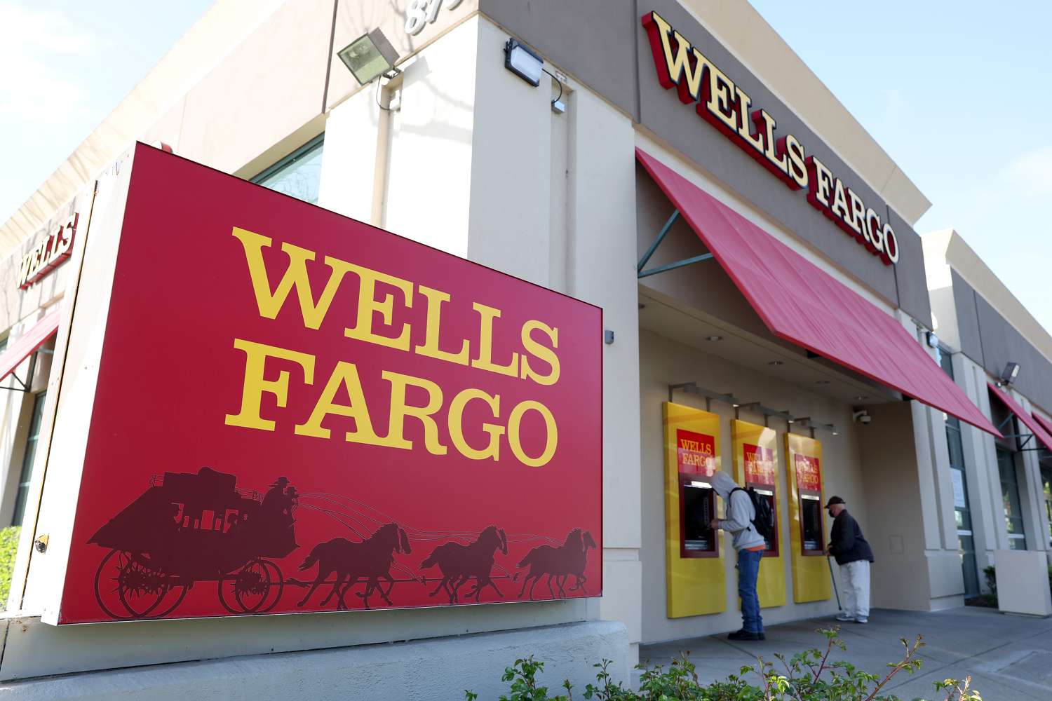 Customers use ATMs at a Wells Fargo Bank