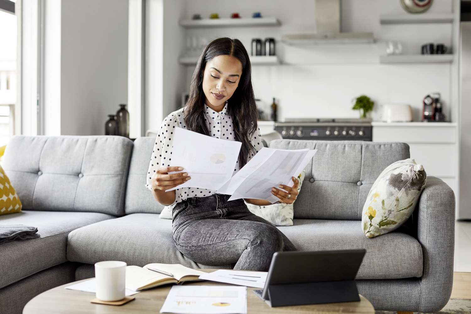 A woman sits on a couch researching the differences between VA and conventional loans.