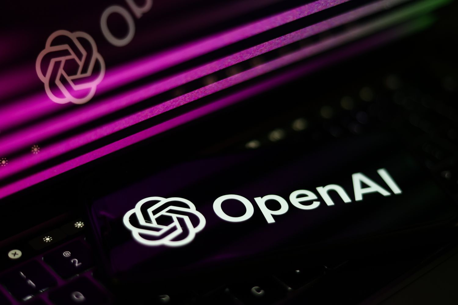 OpenAI website displayed on a laptop screen and OpenAI logo