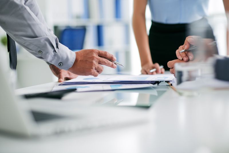 Business executives meet to review SEC forms necessary to file for an upcoming shareholder vote on a planned acquisition.