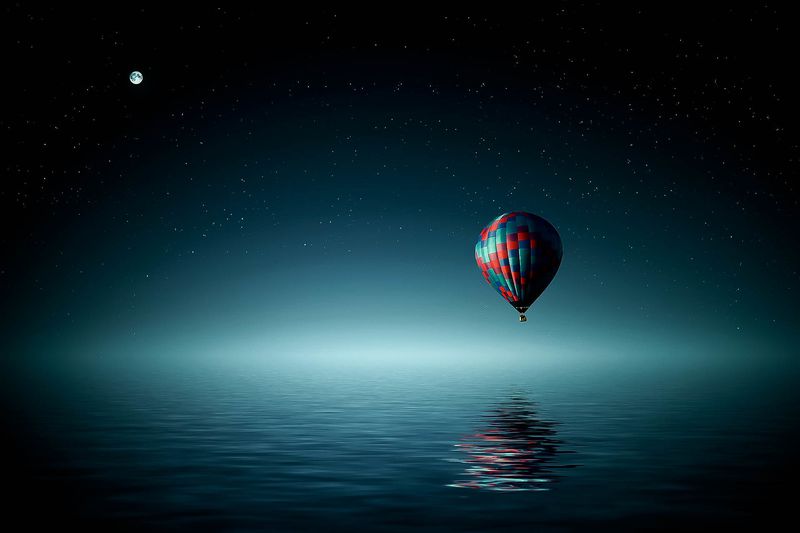 A hot air balloon floating over water at night