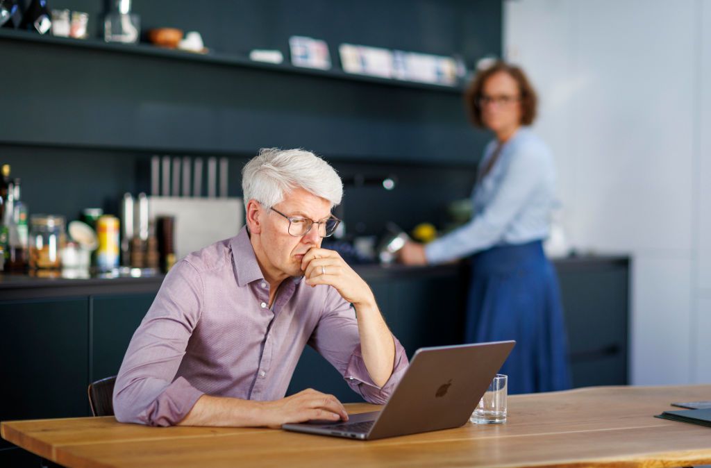 Two older adults in a kitchen with a computer