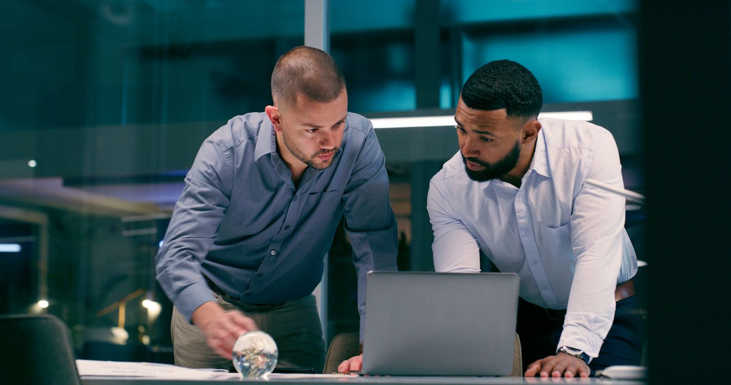 Two male investigators leaning over a computer.