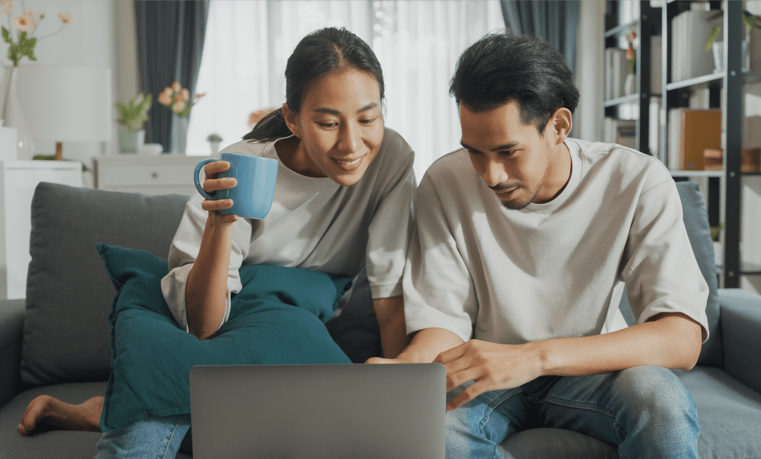 Young couple sitting on their sofa and looking together at mortgage rates on a laptop