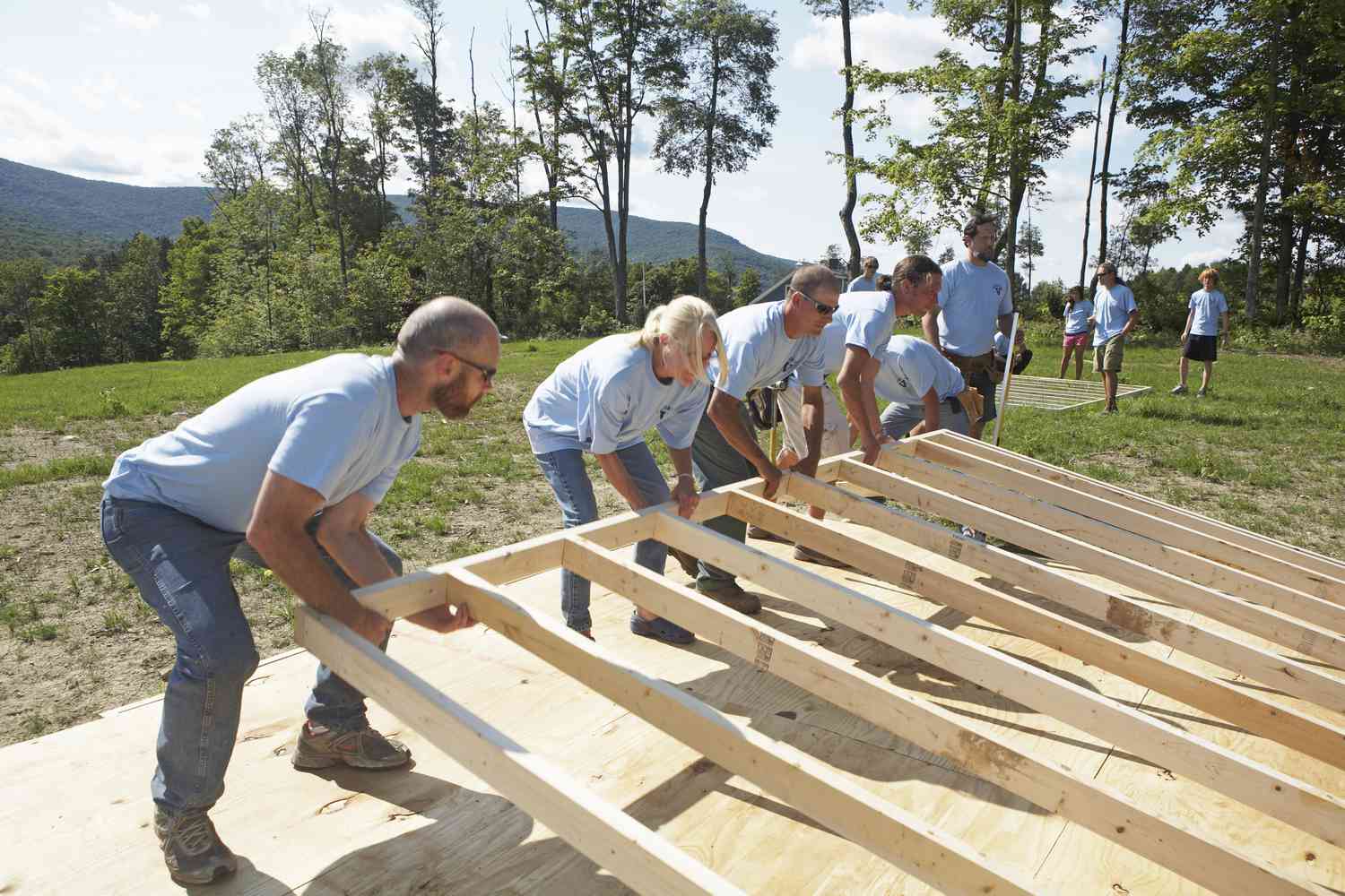 A group of workers raise the wall of a house in a program where they exchange their labor for a labor-time credit on their accounts.