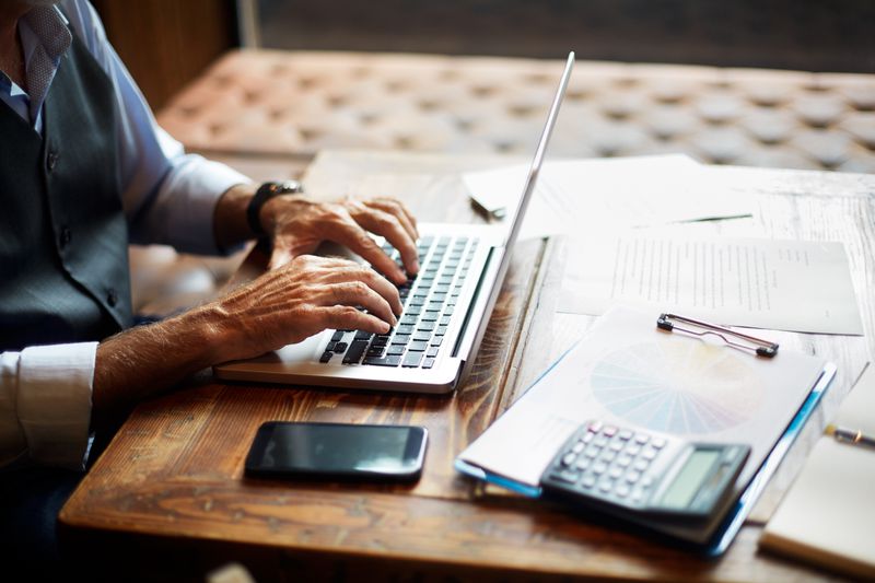 A businessman typing on a laptop in a coworking space.