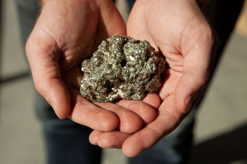 A man's hands hold iron pyrite, the original "fools gold"