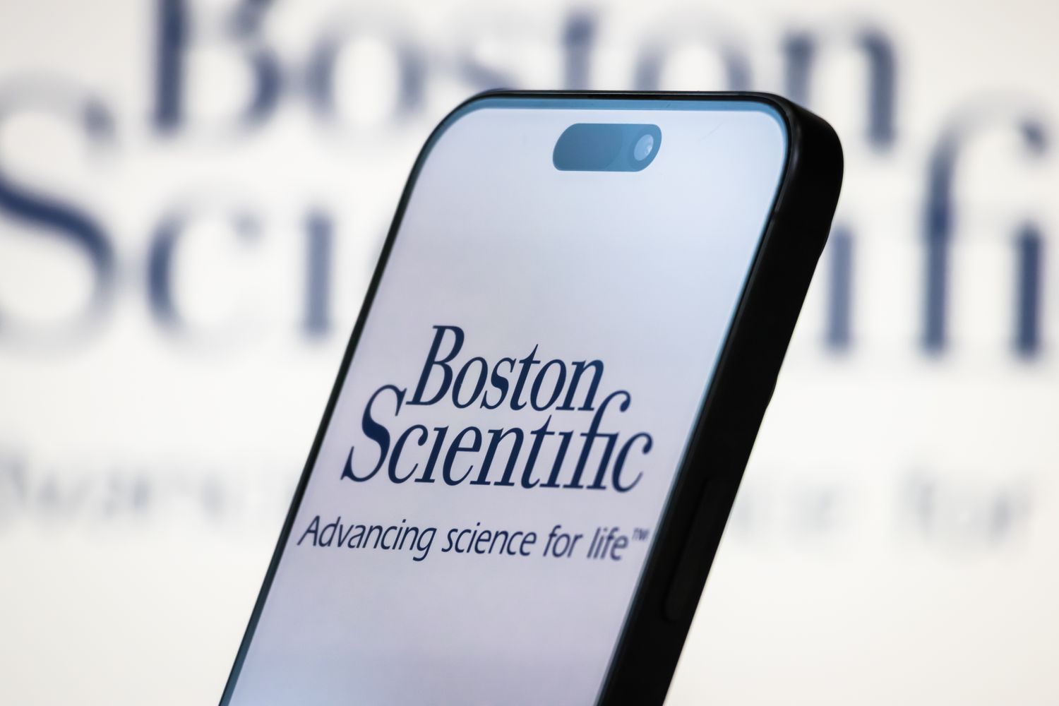 The logo of Boston Scientific Corporation is displayed on a smartphone screen, with the company's branding and slogan Advancing science for life in the background