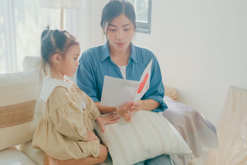 Mother reading a card to daughter