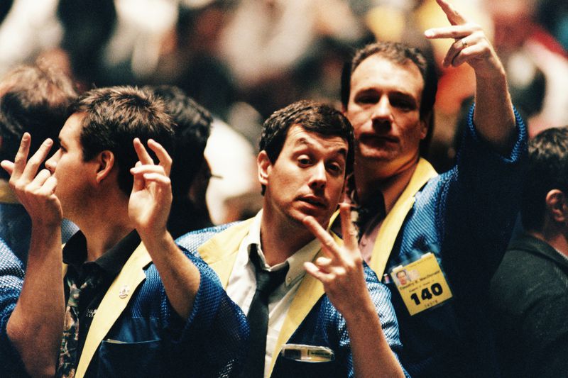 Traders on the floor of the Chicago Board of Trade gester to buy and sell securities.