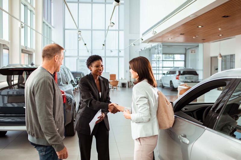 Couple picking up their new car at the dealership