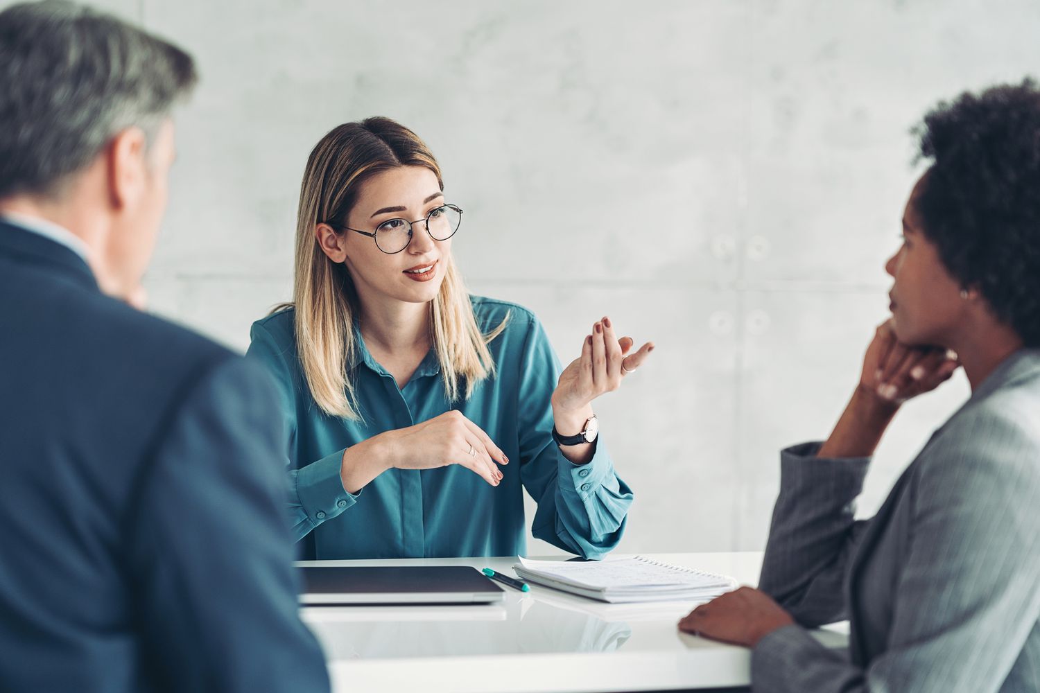 Three people have a discussion in an office setting.