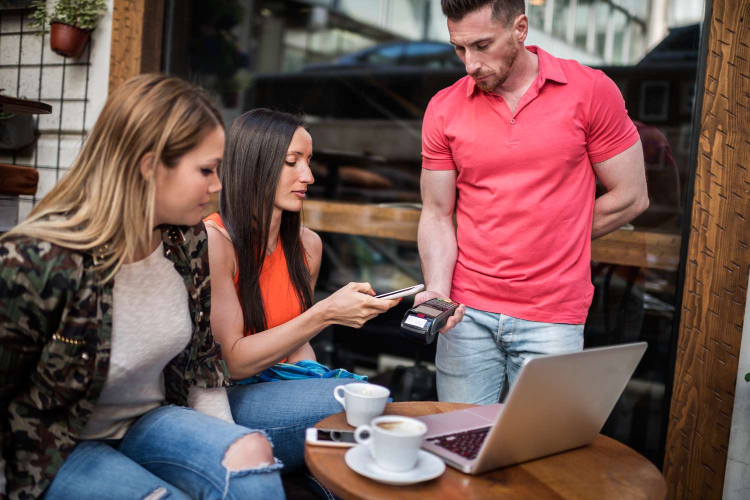 Female customers paying with mobile phone over credit card reader