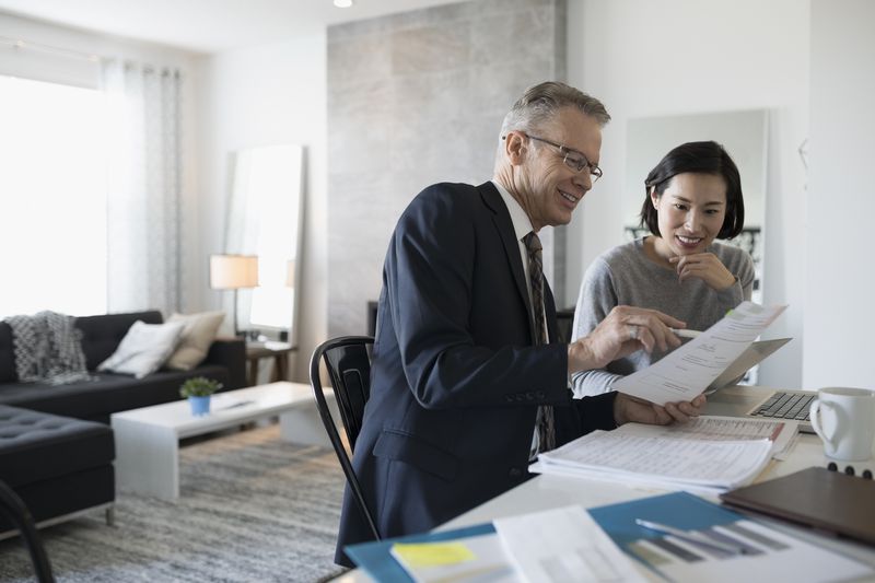 Financial advisor and woman with laptop meeting in dining room.