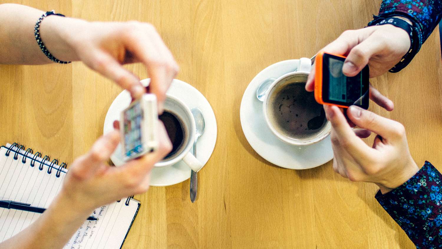 Two people in a cafe sending a peer-to-peer money exchange via their iPhone smartphones