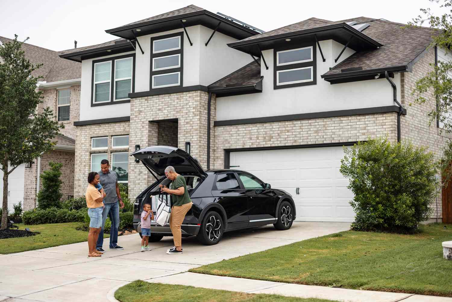 A happy family in front of the house they bought with locked-in interest rate mortgage.