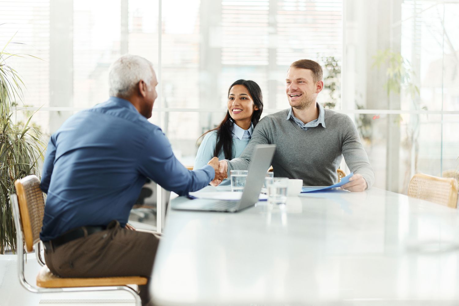 Three people in a meeting, with the two men shaking hands