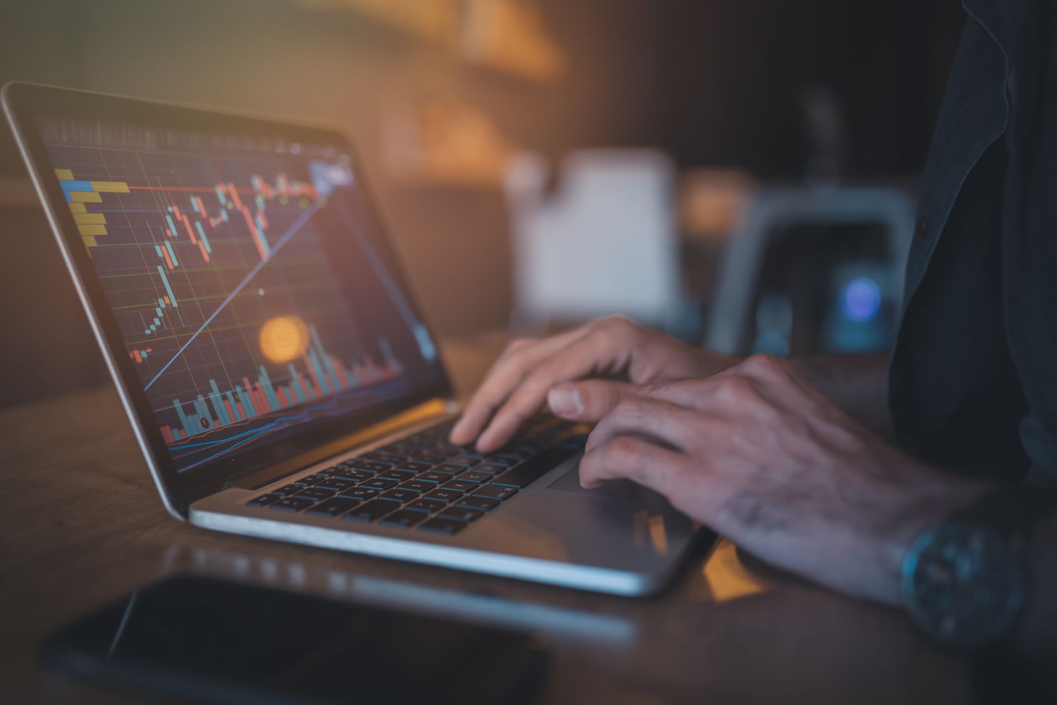 Stock trader on a laptop looking at charts of trade information