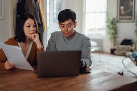 Young couple at their dining room table looking together at mortgage rates on a laptop