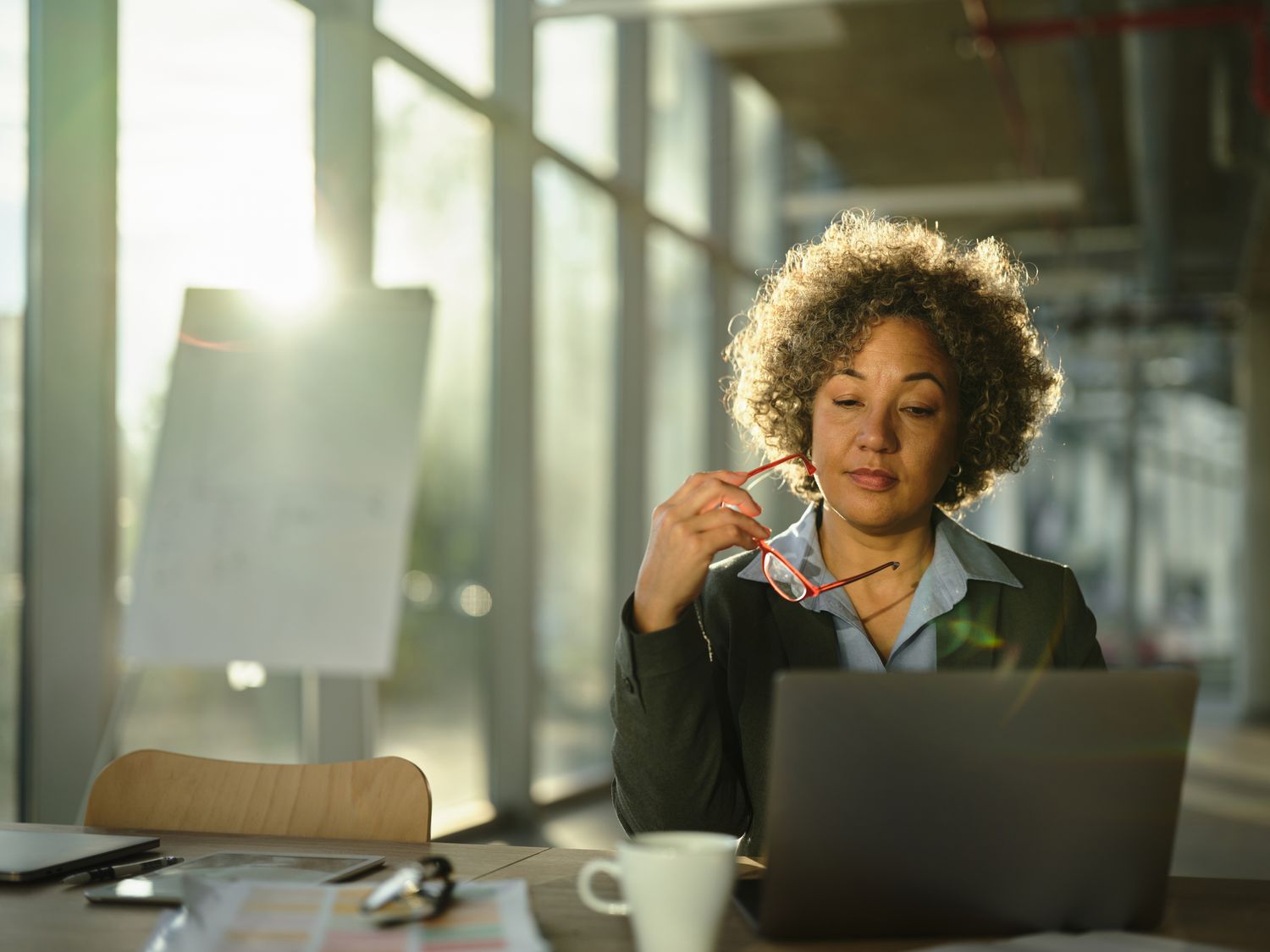 Woman reading on a laptop in an office setting. 
