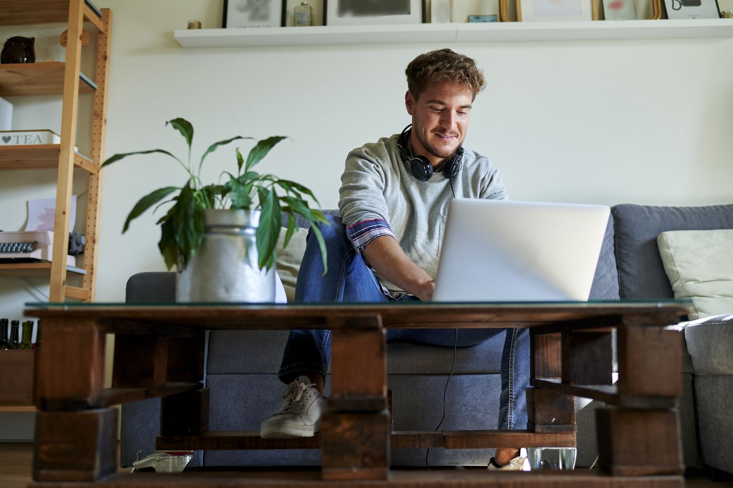 A man using laptop while sitting on the sofa in the living room to apply for a credit card.