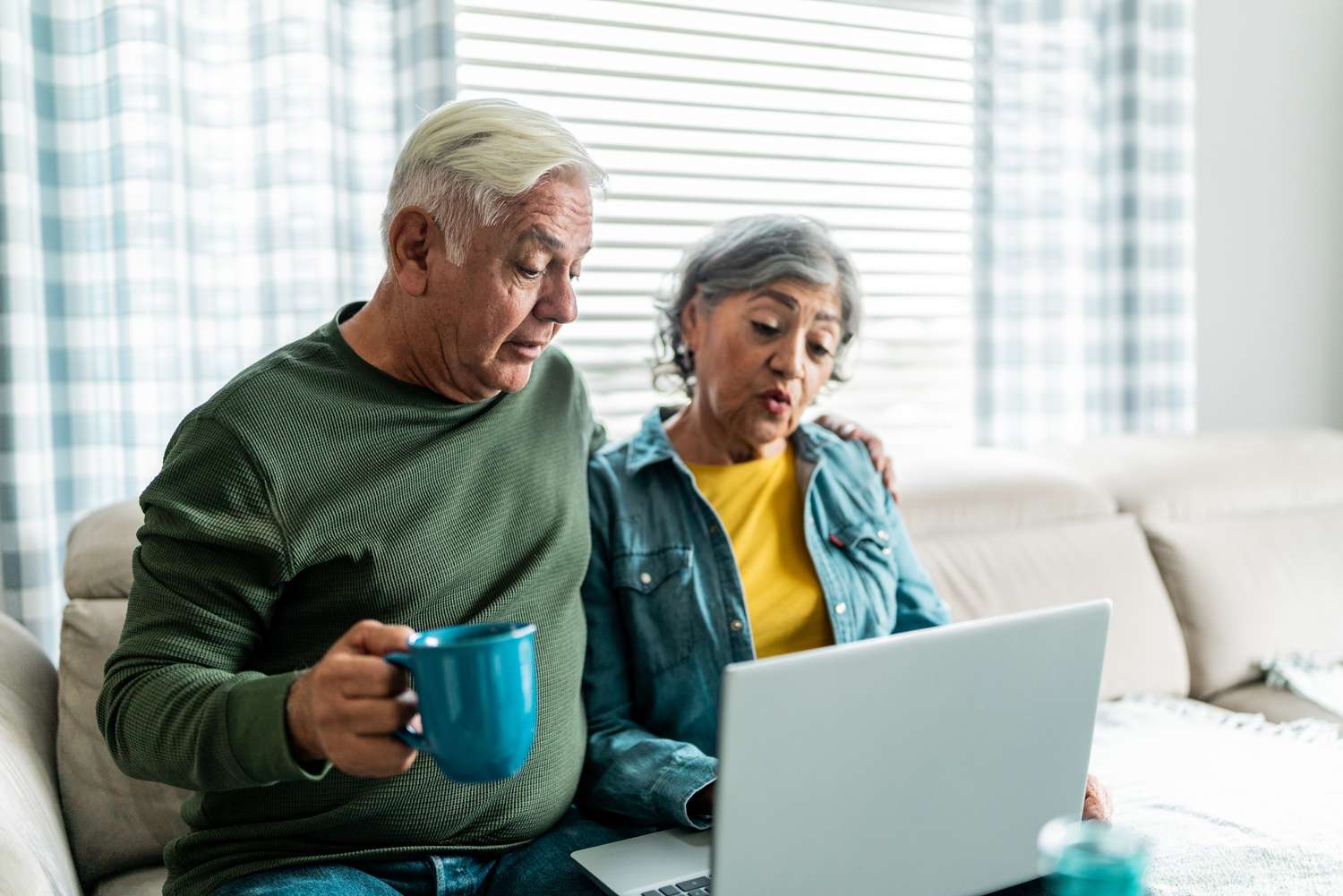 Older couple sitting on their sofa and looking at mortgage rates on a laptop