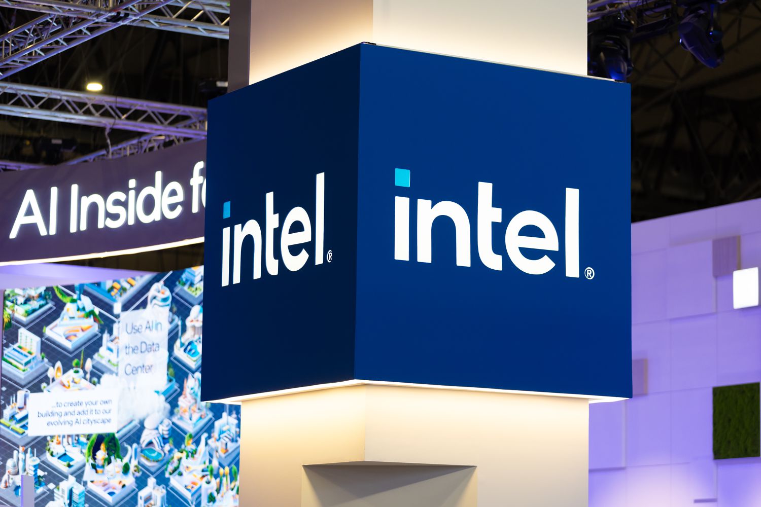 The Intel logo is seen on a blue sign on a pillar inside a conference hall.