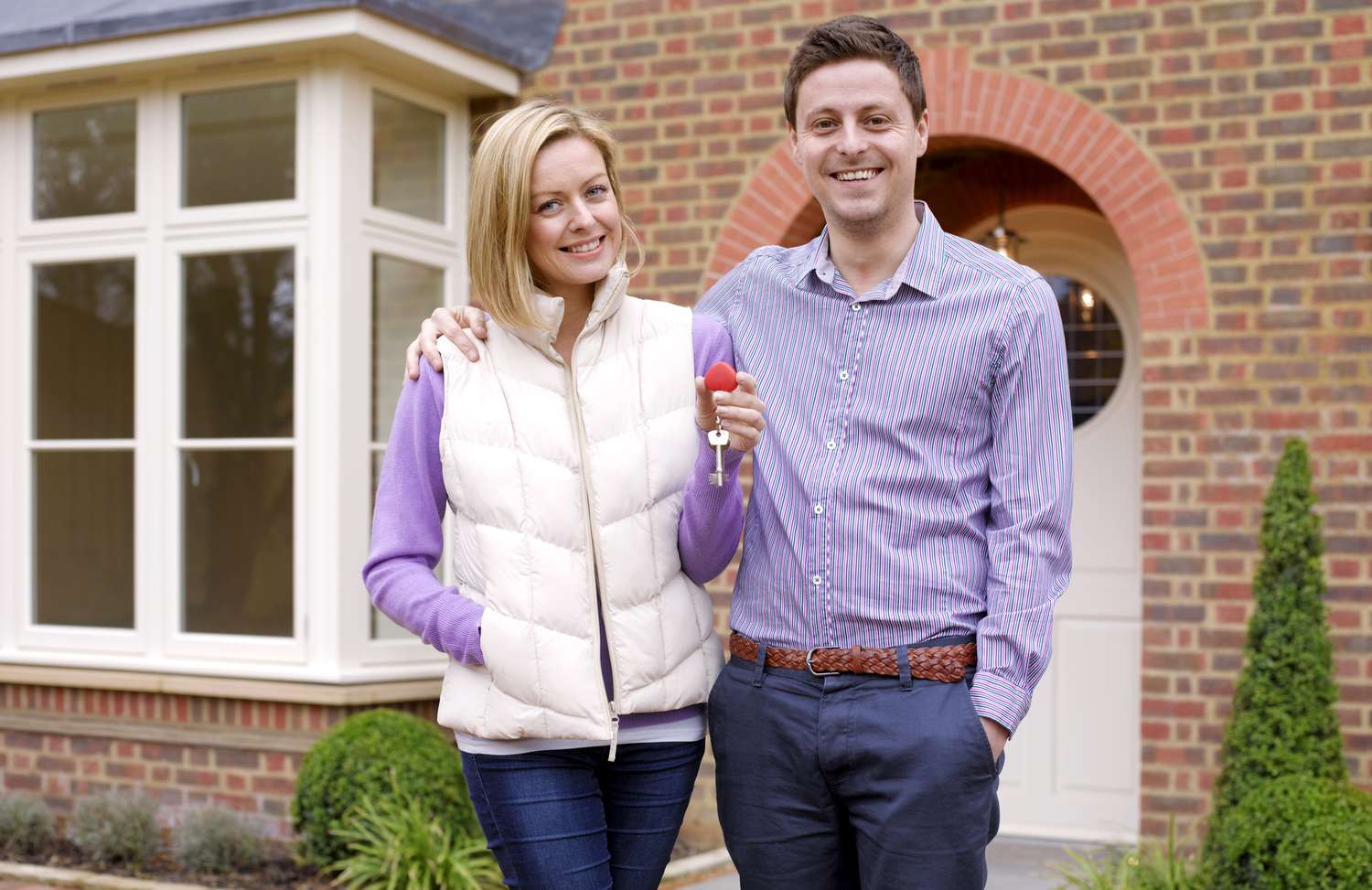 Couple holding keys to their house in front of their house