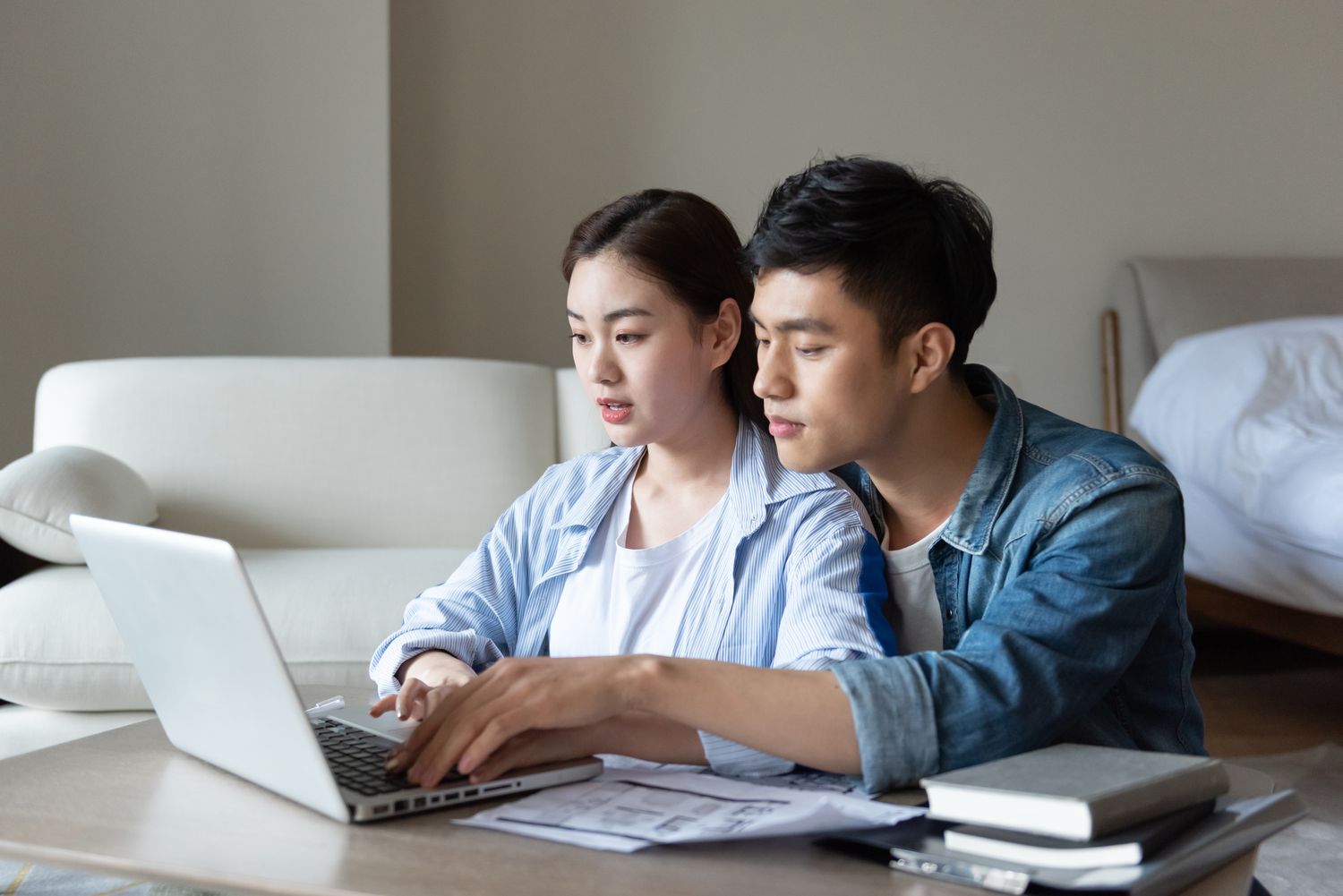 Couple sitting at home while looking at the difference between soft and hard credit check on laptop.