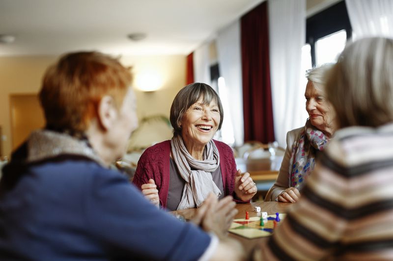 Older women sitting around a table playing a board game.