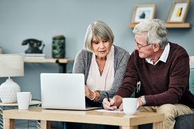 Older couple sitting at home and looking together a mortgage rates on a laptop