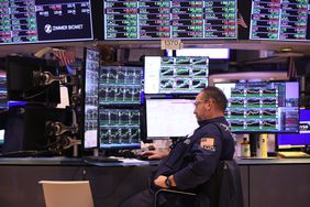 A trader sits at a desk in front of several computer screens on the floor of the New York Stock Exchange.