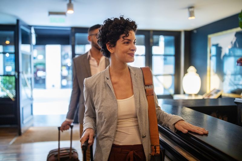 Business travelers arriving at hotel reception desk.