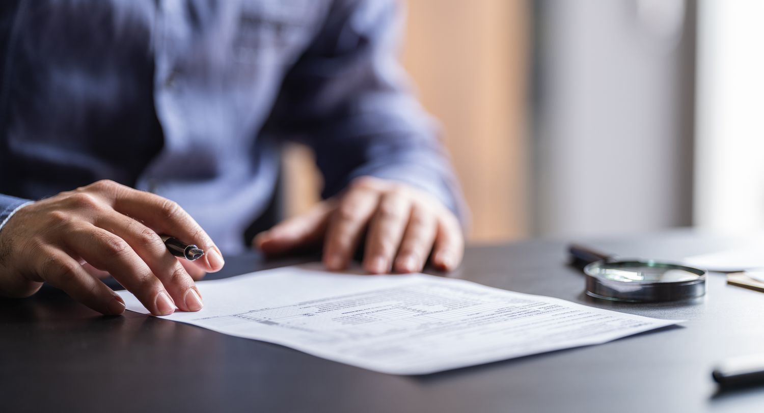 Close up of man sitting at desk with pen in hand about to fill out form
