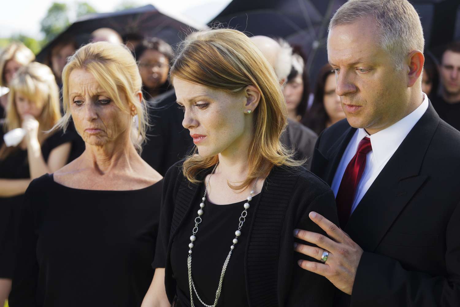 A grieving family standing graveside at a funeral.