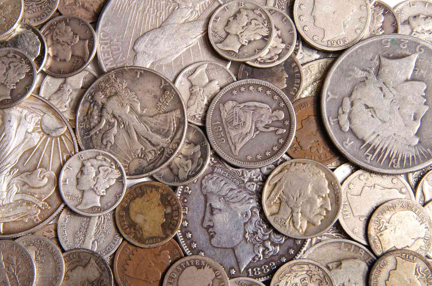 A close-up of a collection of antique silver coins lay spread out on a surface